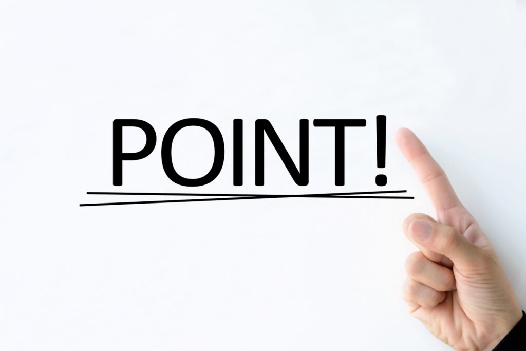 ホワイトボードに書かれたポイントの文字を指差す人物の手