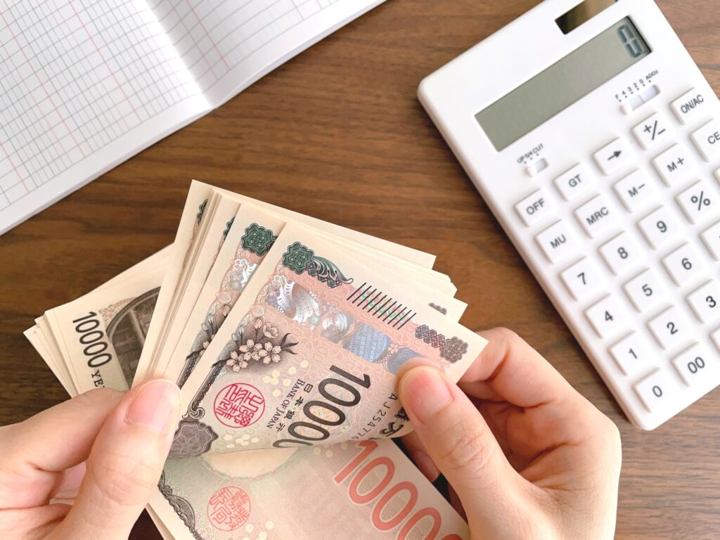 お金を数える女性の手と机上の白い電卓