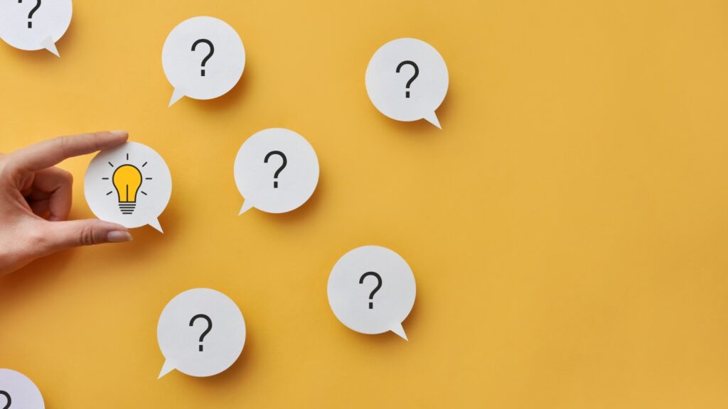 多くの質問と電球を持つ手。問題解決とクリエイティブなアイデアの検索。