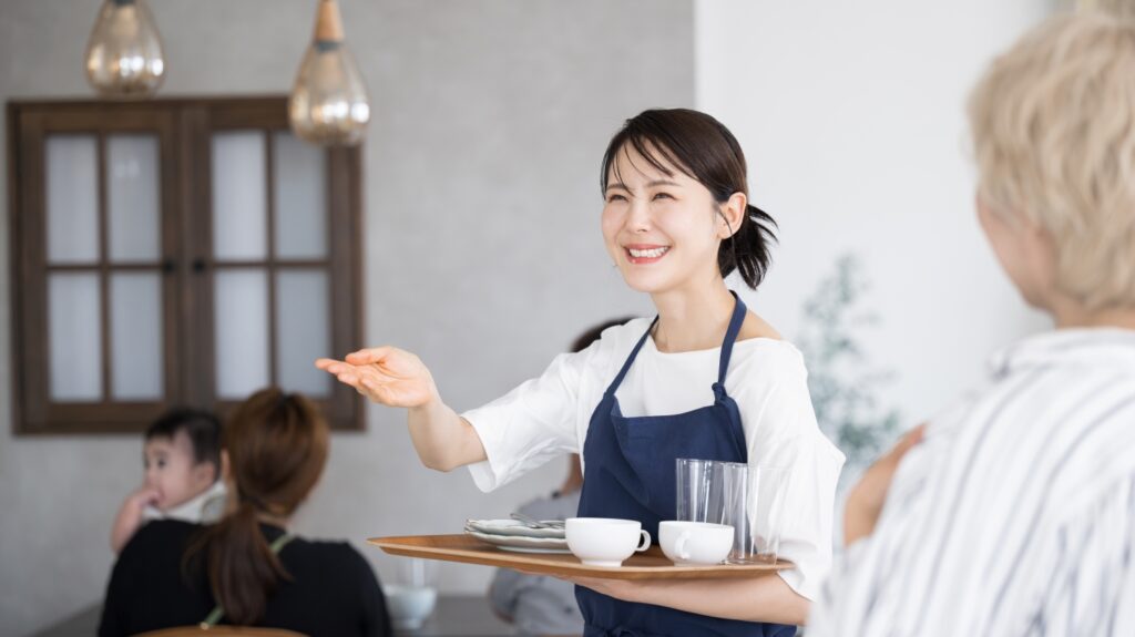 いらっしゃいませとお客を案内するカフェや飲食業、レストランのスタッフ