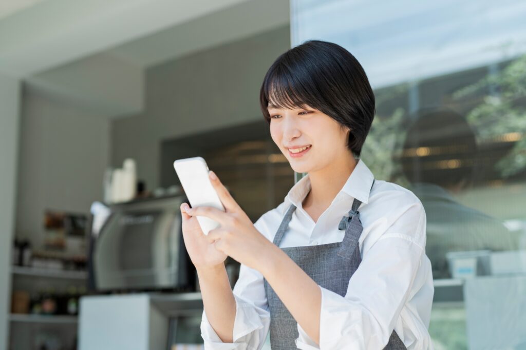 カフェ スマートフォンを使う女性スタッフ