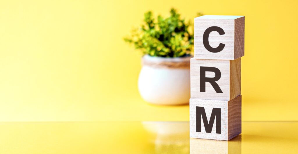 文字付きの3つの木製キューブ - CRM - 顧客関係管理、青いテーブルの上、左側にテキスト用のスペース