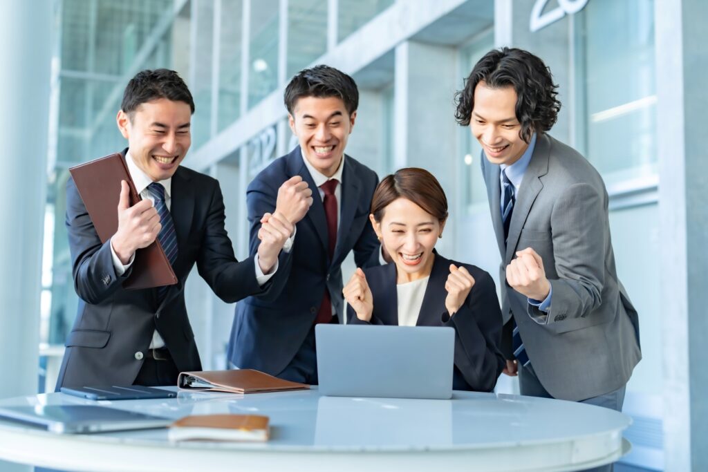 ビジネスマンたちが全員でガッツポーズして喜ぶ姿